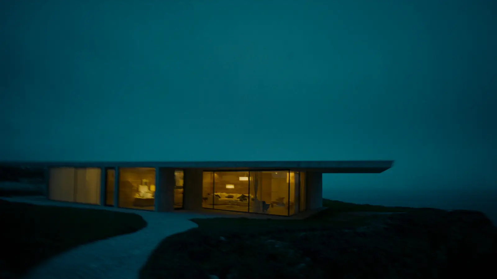 The concrete pavilion's glowing glass facade at dusk, seen from the path