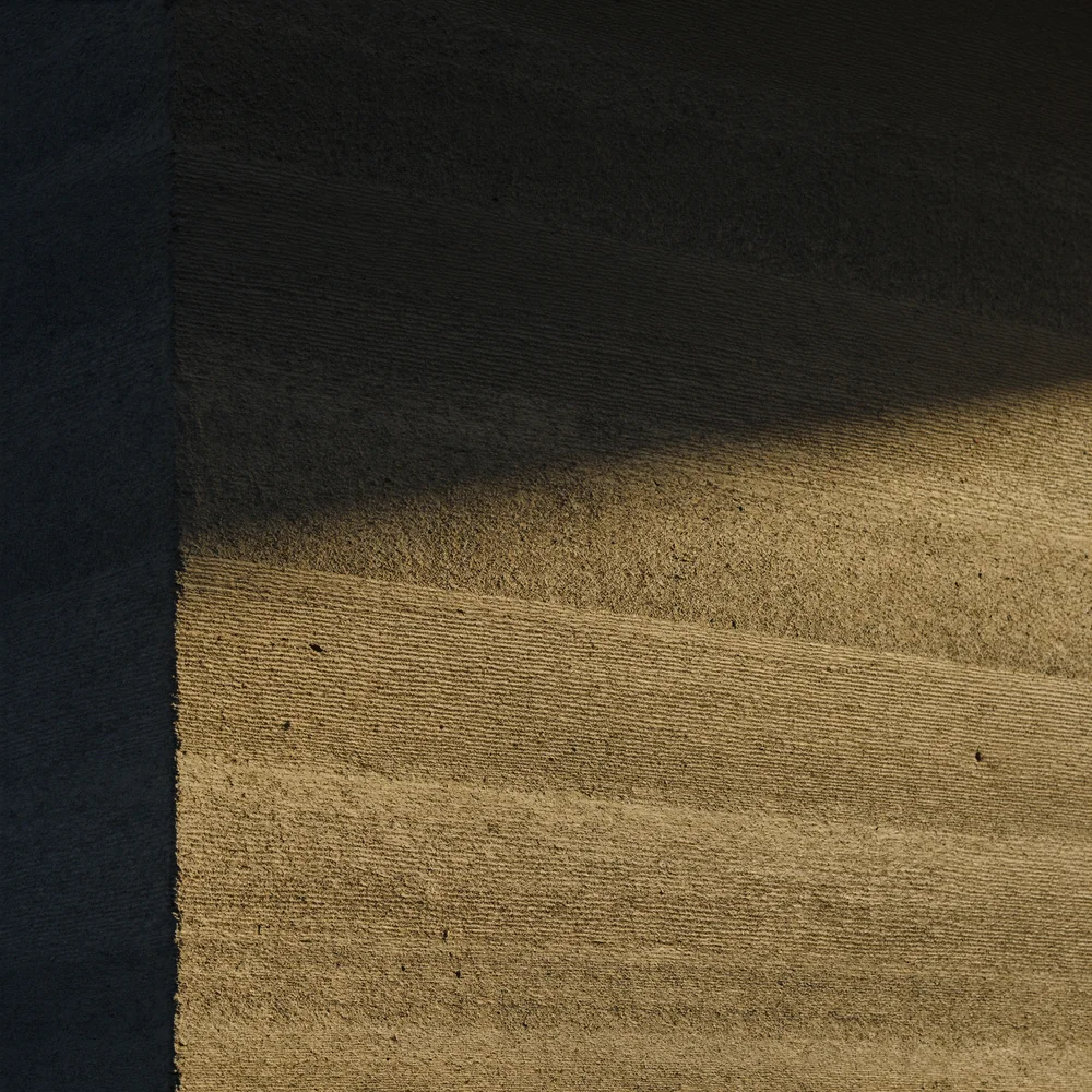 Board-formed concrete showing timber grain in low golden light
